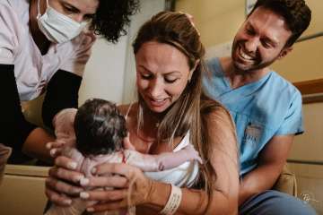 Joyful moment: new parents hold their newborn in the delivery room