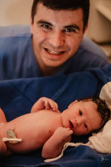 Father happily holds newborn baby in hospital after successful delivery