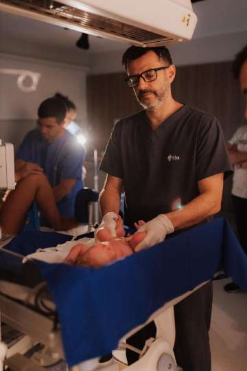 A health care worker helps the newborn in a well-lit delivery room, focusing on moments of care